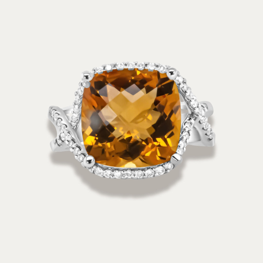 Ring with a large yellow citrine gemstone and smaller diamonds on a light gray background