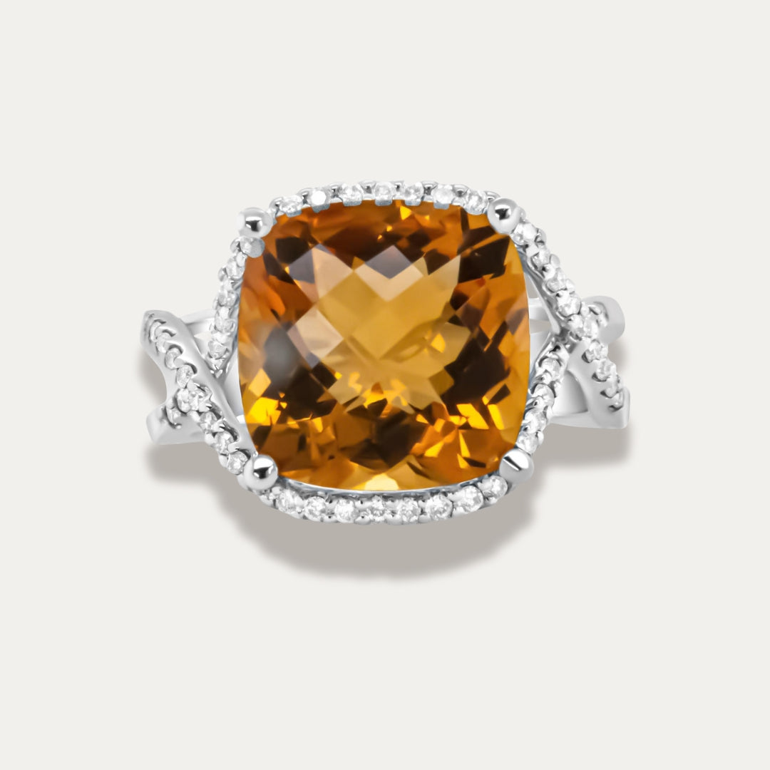 Ring with a large yellow citrine gemstone and smaller diamonds on a light gray background