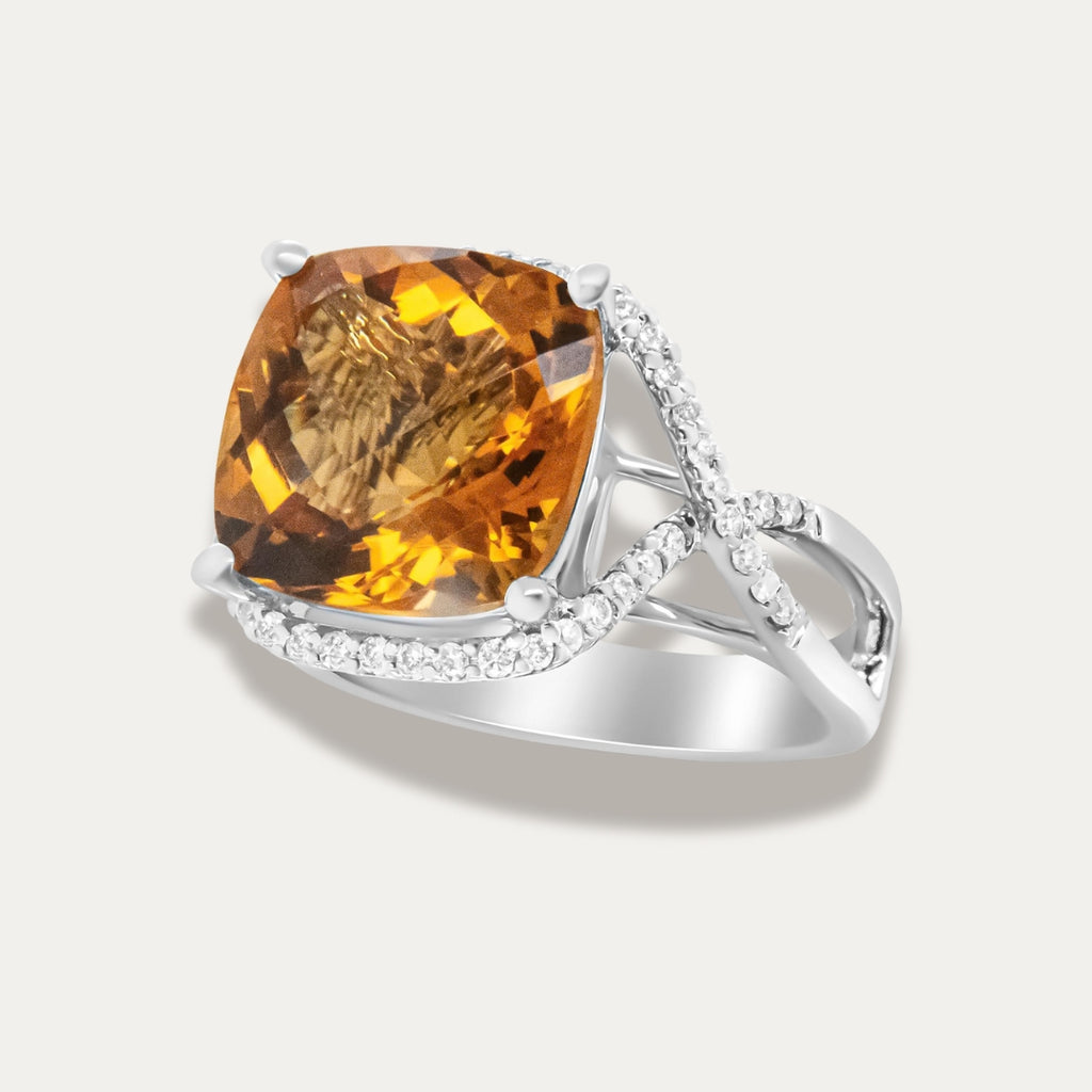 Ring with a large yellow citrine gemstone and smaller diamonds on a light gray background
