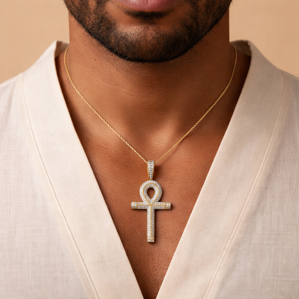 Man wearing a yellow gold and diamond necklace with an ankh pendant against a beige background