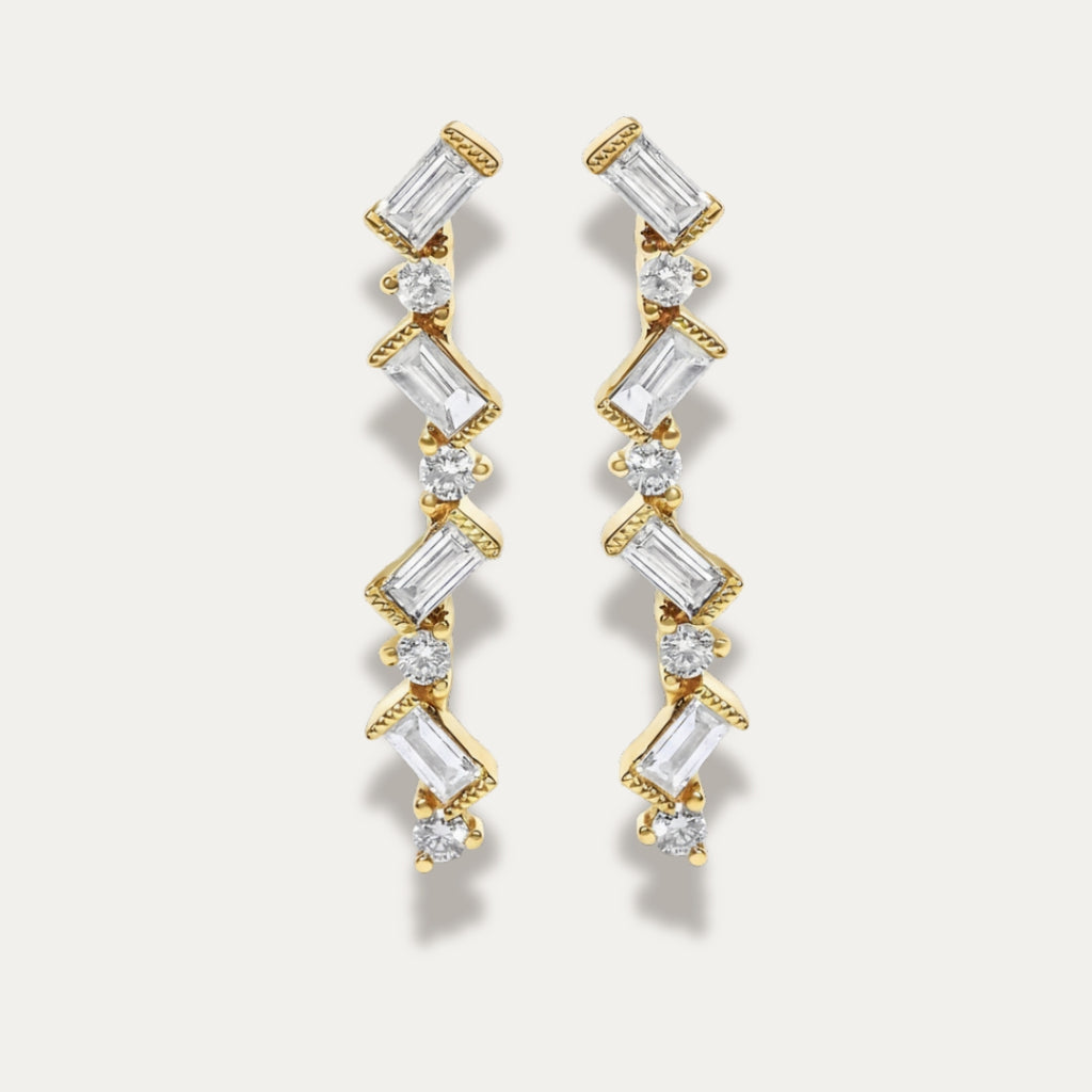 Gold zigzag earrings with diamonds on a light gray background