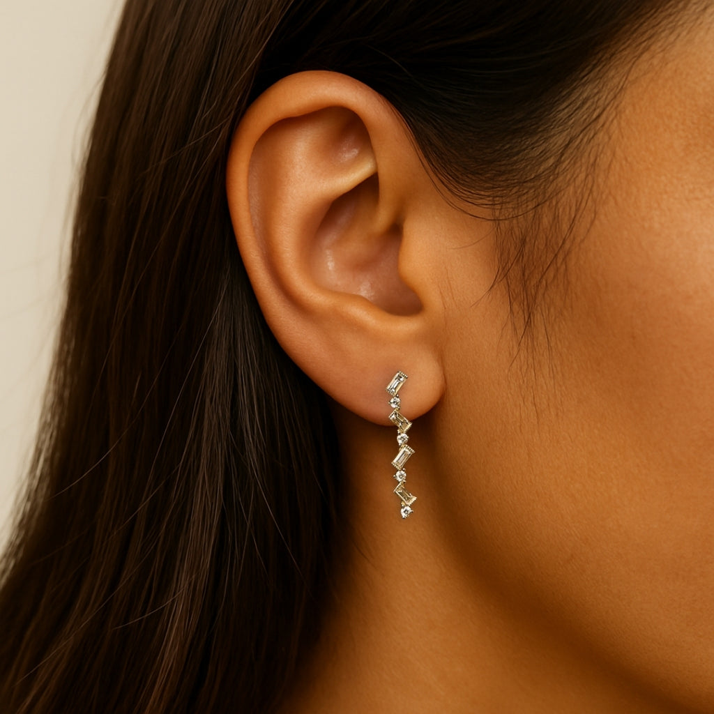 Close-up of an ear wearing a delicate earring with a neutral background