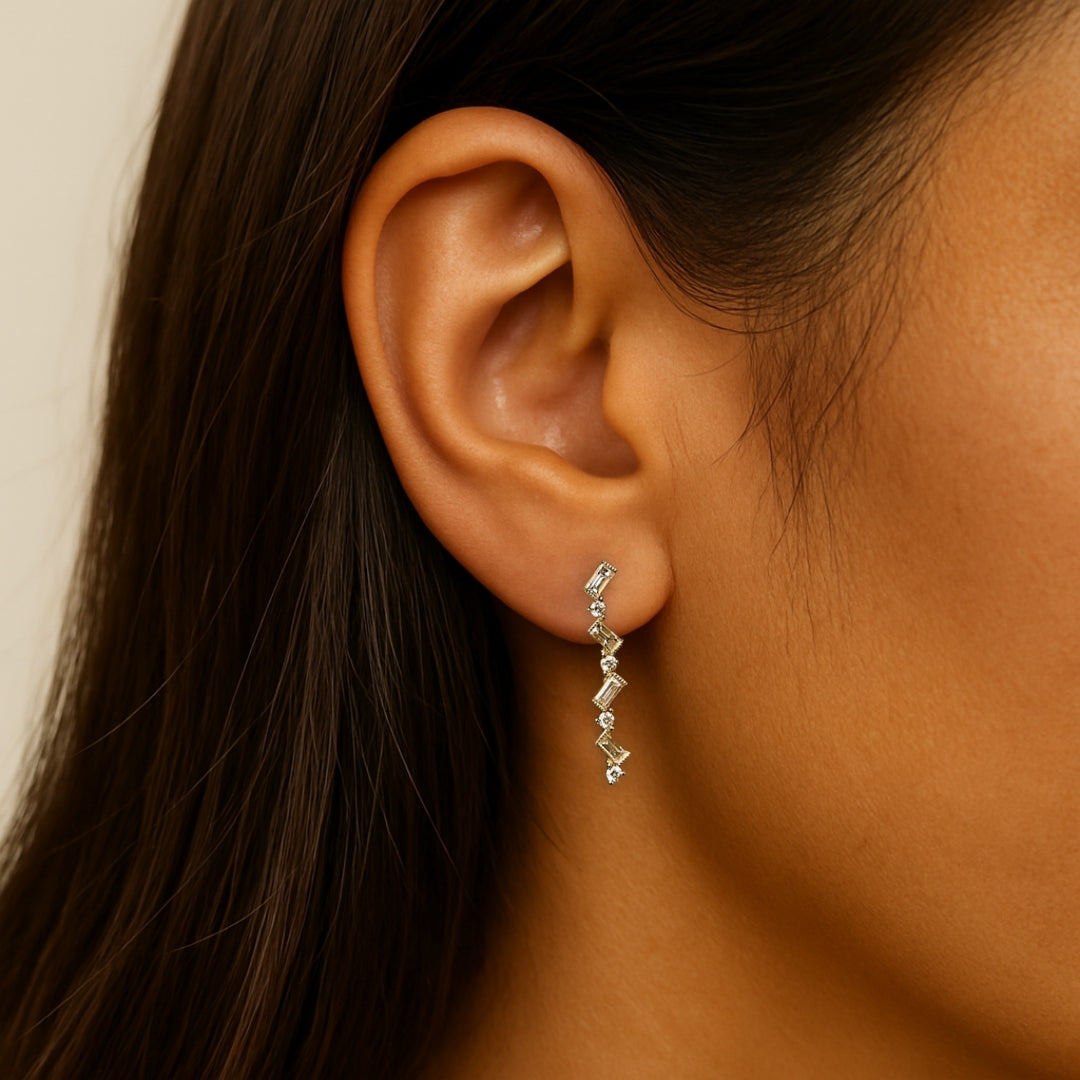 Close-up of an ear wearing a delicate earring with a neutral background