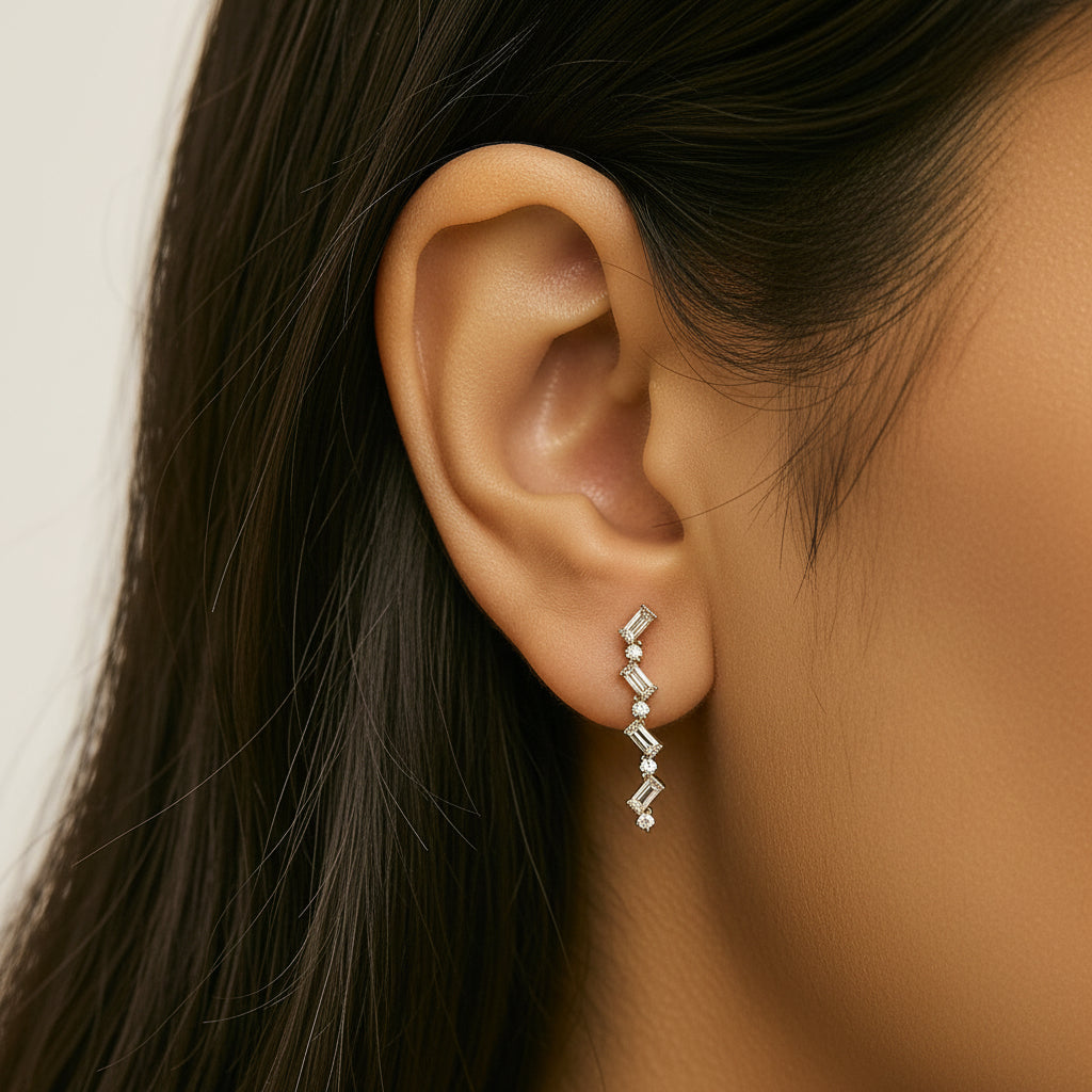 Aureline Zig Zag Drop Earrings hanging delicately on a model’s earlobe, with diamonds catching the light, smooth skin, minimal background, elegant and timeless.