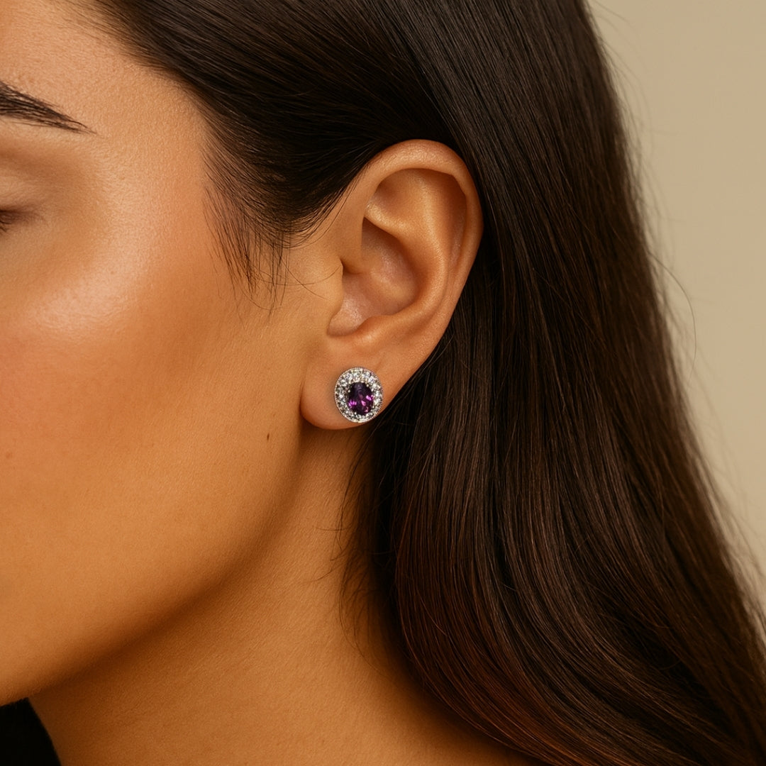 Close-up of a woman wearing a pair of garnet earrings with a beige background