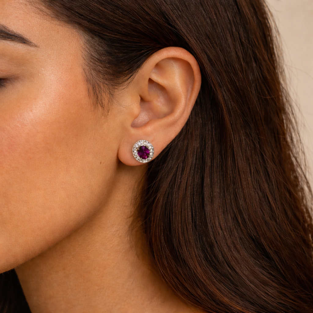 Close-up of a woman wearing a pair of garnet and diamond earrings with a beige background