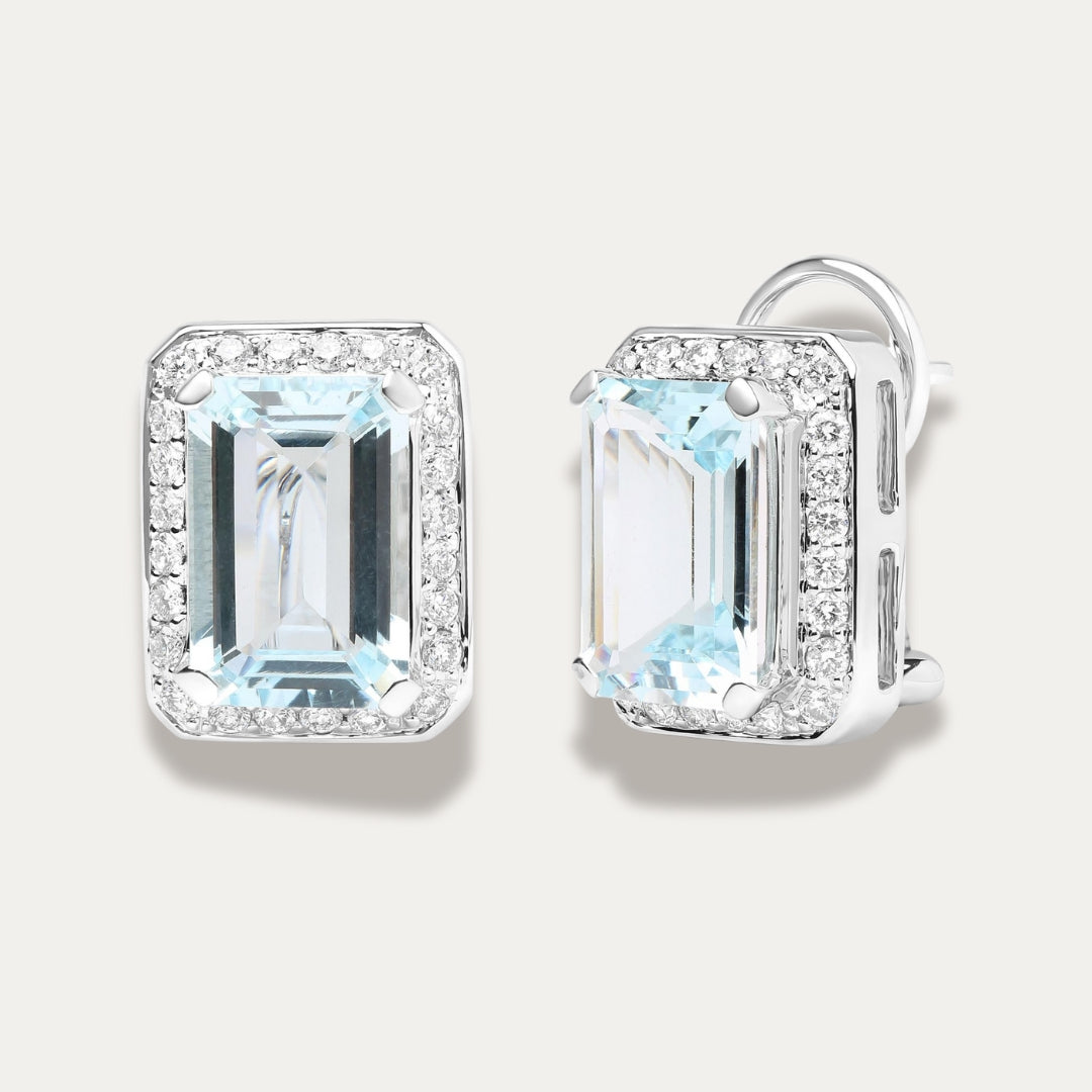 Pair of emerald-cut aquamarine gemstone 18K white gold earrings with diamond accents on a light gray background