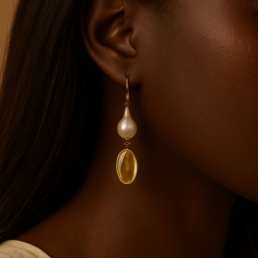 Woman wearing earring with large pearl and yellow citrine on a beige background