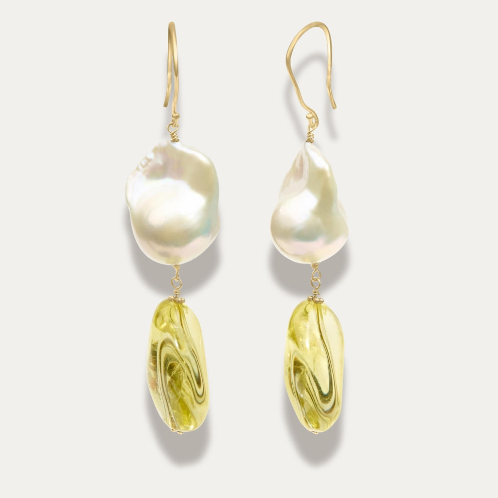 Pair of earrings with large pearl and yellow citrine on a light gray background