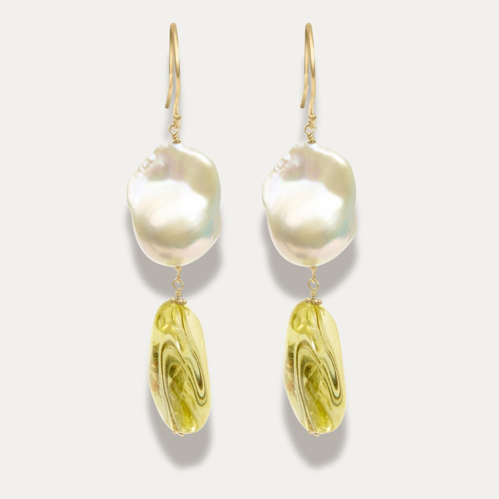 Pair of earrings with large pearl and yellow citrine on a light gray background