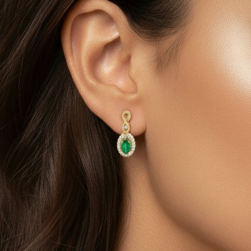 Close-up of an ear wearing a gold and emerald green earring.
