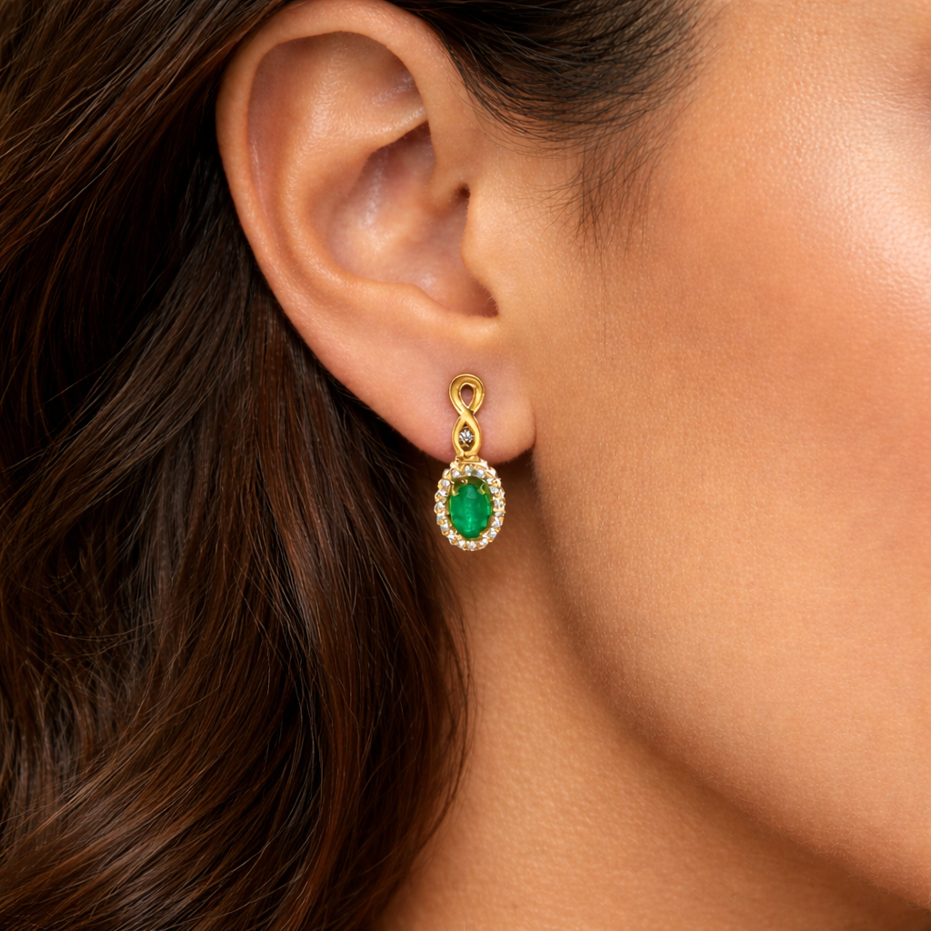 Close-up of a woman's ear wearing a gold and emerald green earring.