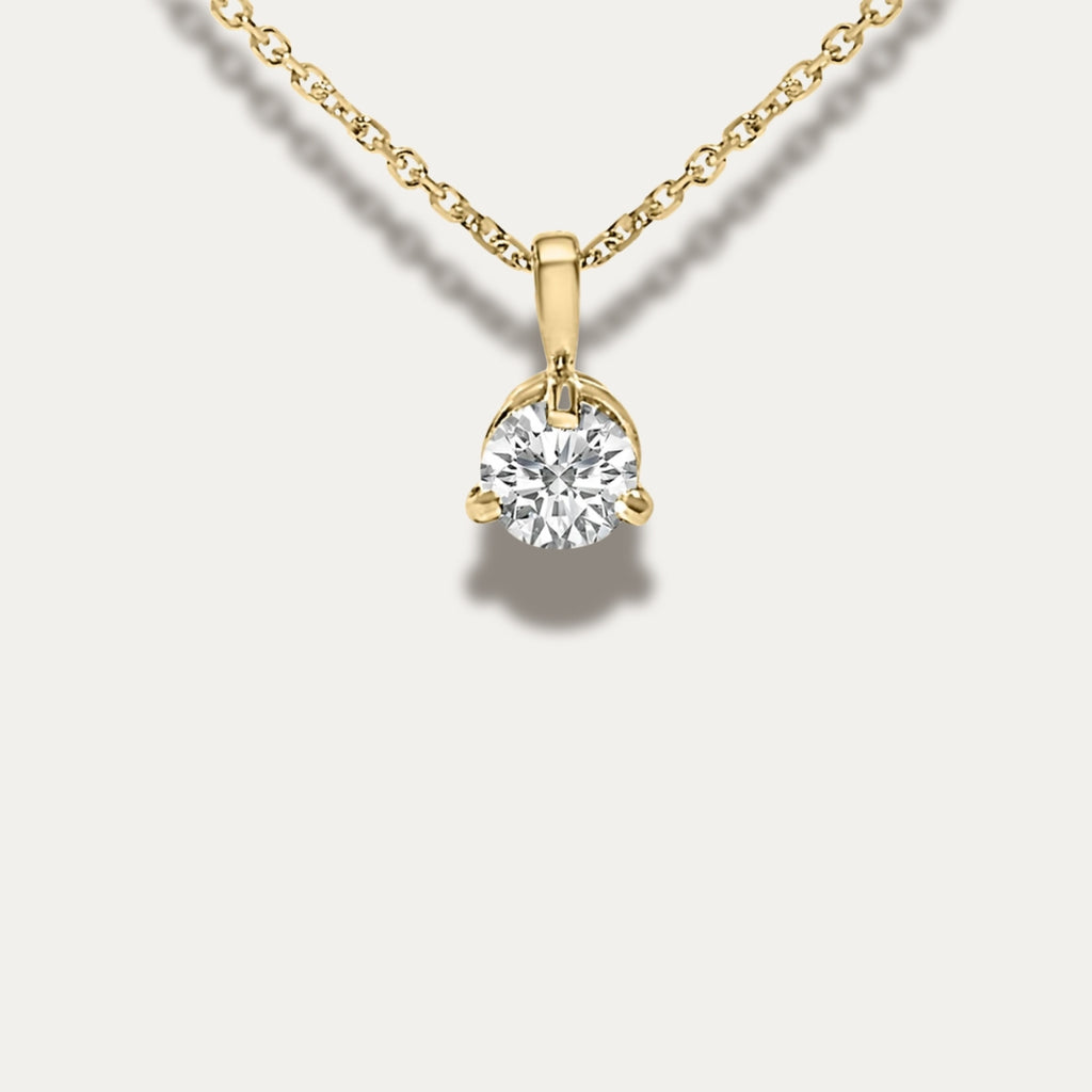 Gold necklace with a diamond pendant on a light gray background