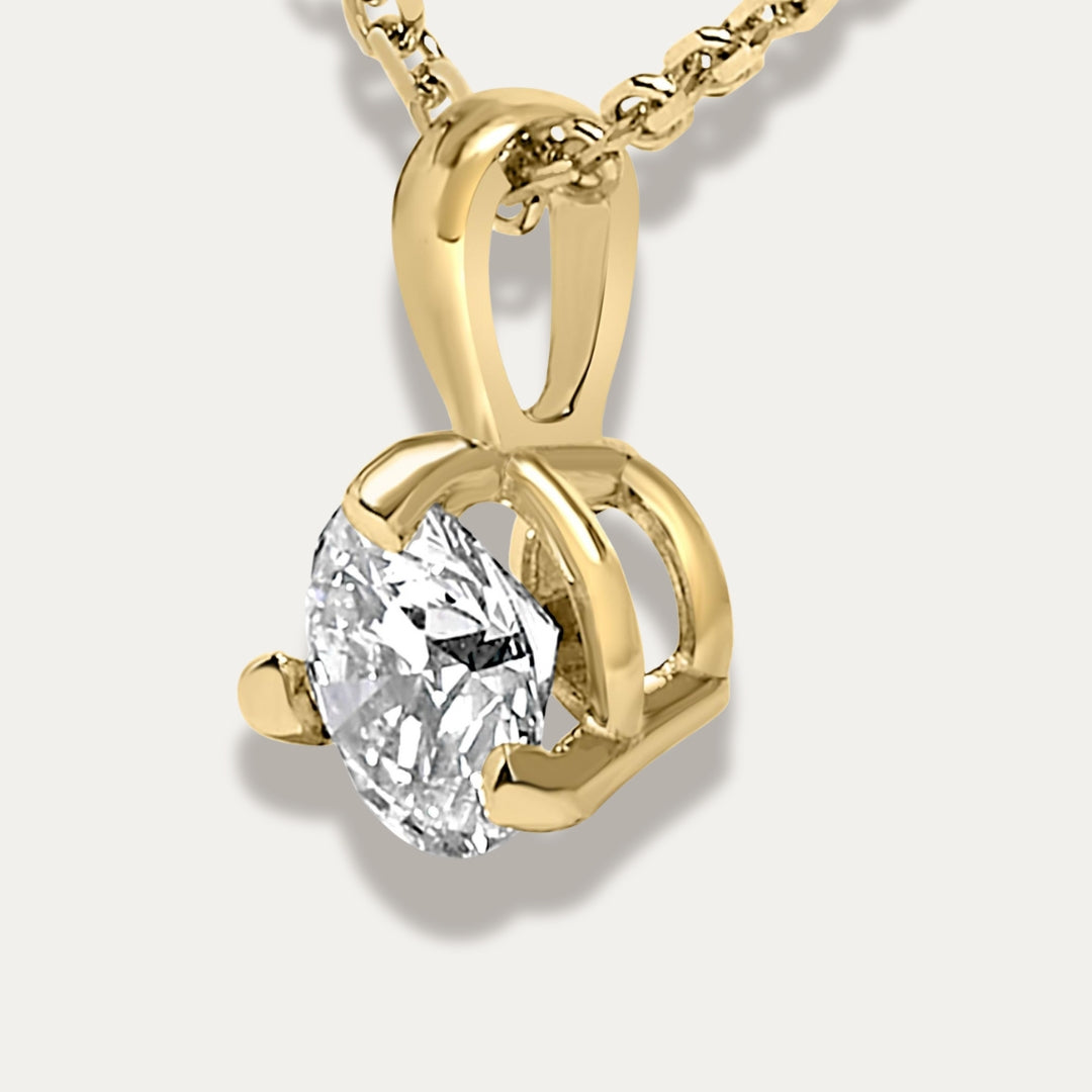 Gold pendant with a clear gemstone on a light grey background