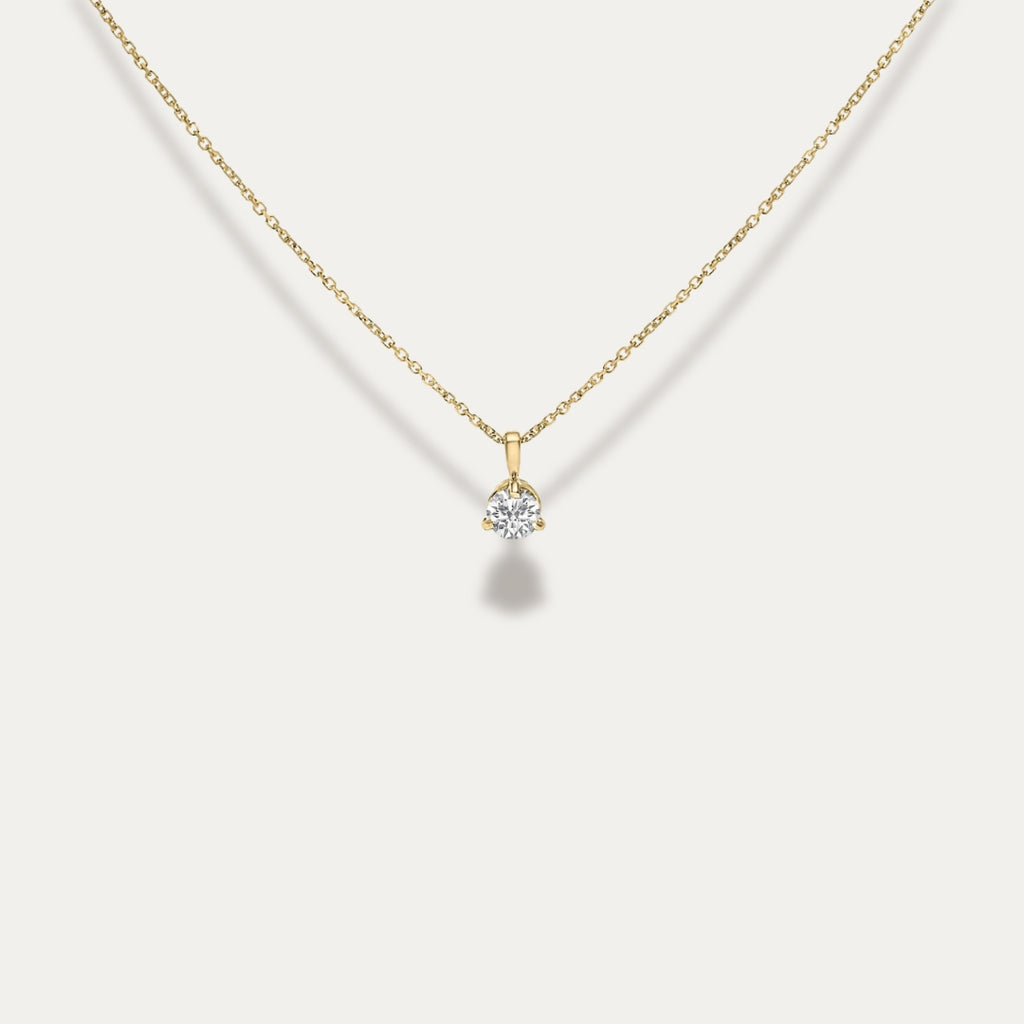 Gold necklace with a diamond pendant on a light gray background
