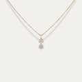 Gold necklace with a diamond pendant on a light gray background