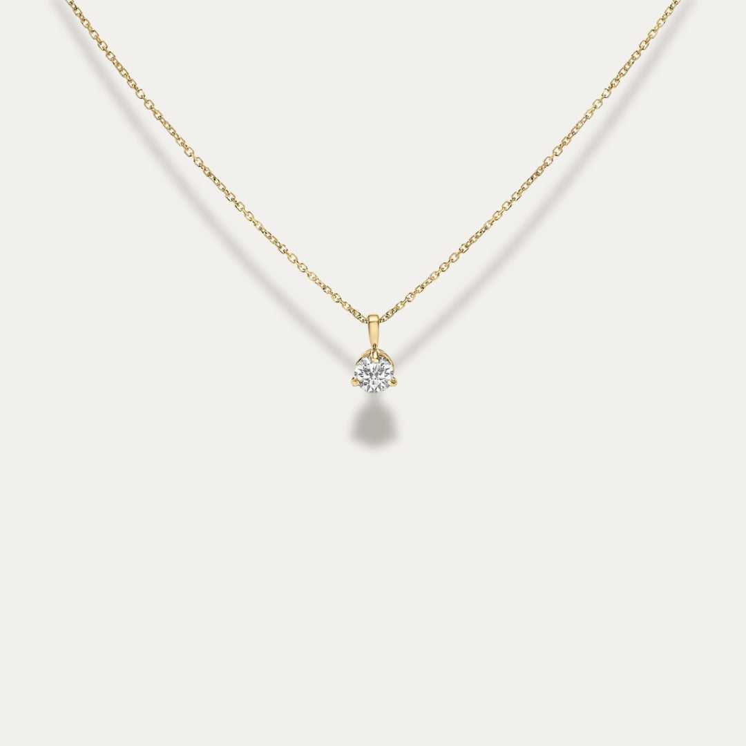Gold necklace with a diamond pendant on a light gray background