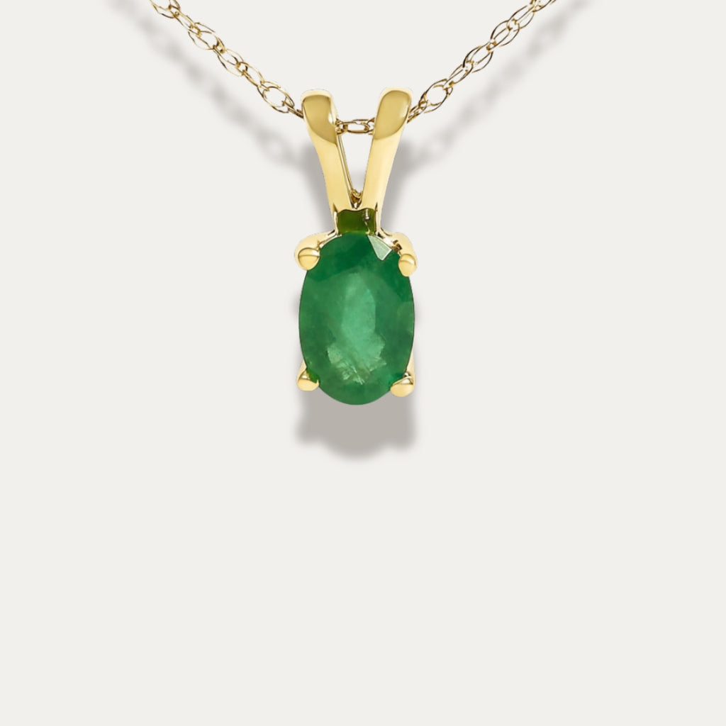 Gold pendant with a emerald green gemstone on a white background