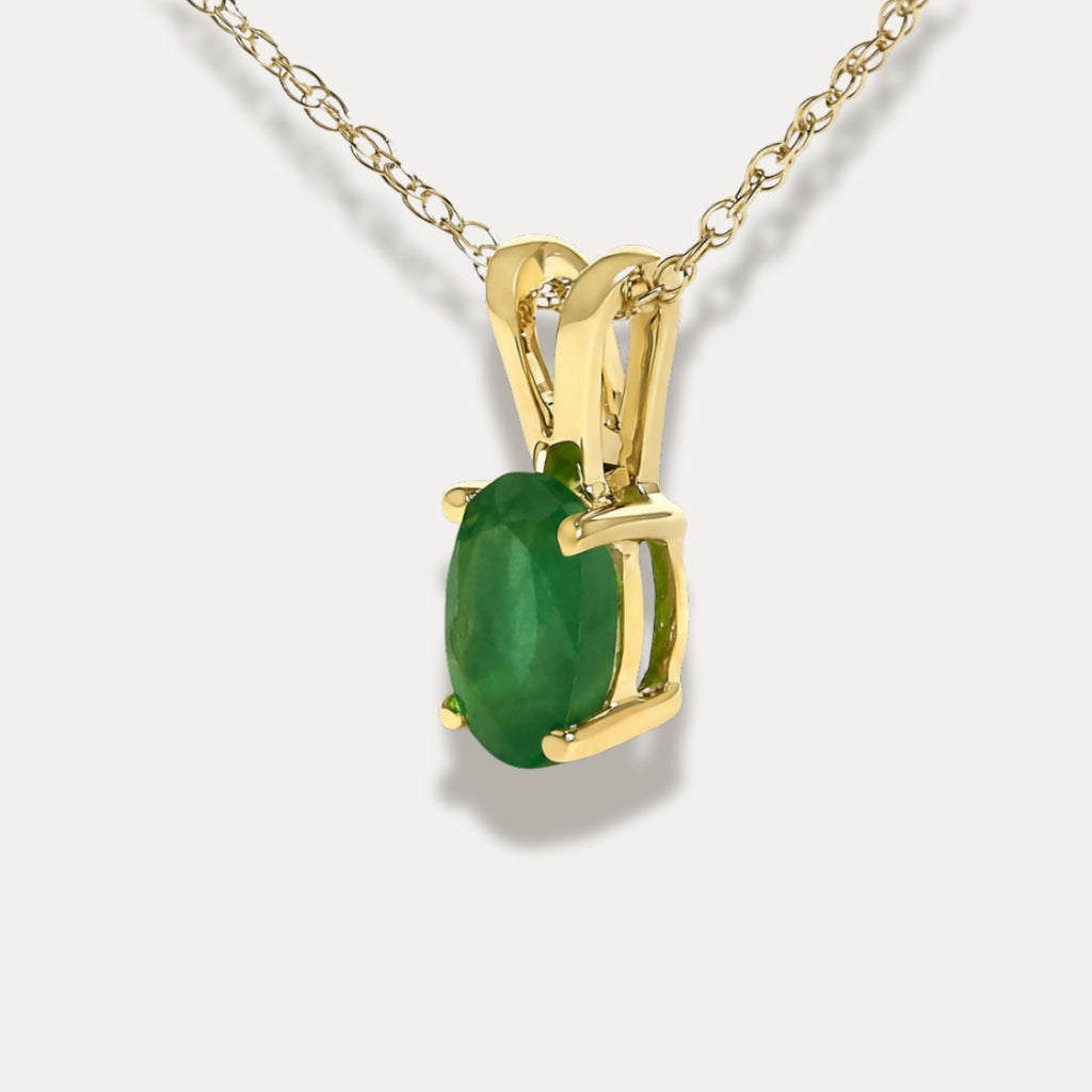 Gold necklace with a emerald green gemstone pendant on a white background