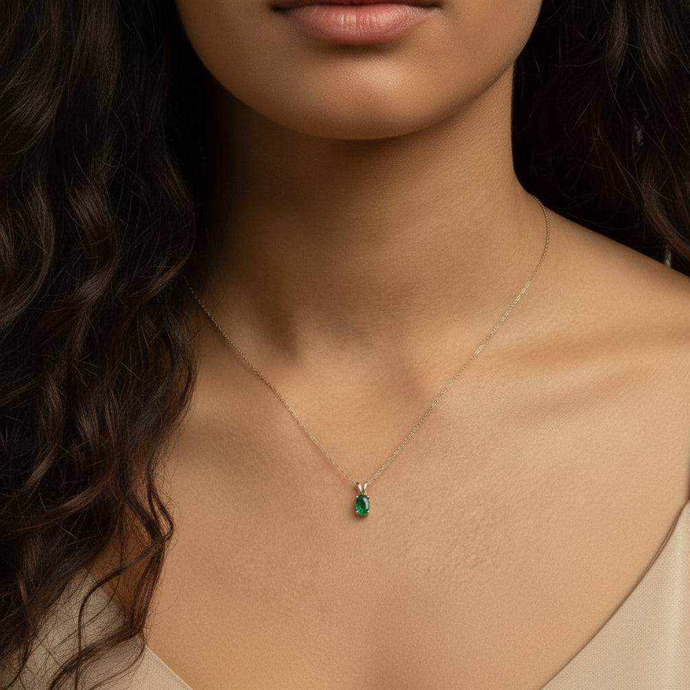 Model wearing the Esmé Solitaire Pendant Necklace by Teraju, featuring a green emerald in 14K yellow gold on an 18-inch rope chain.