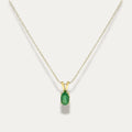 Gold necklace with an emerald green gemstone pendant on a white background