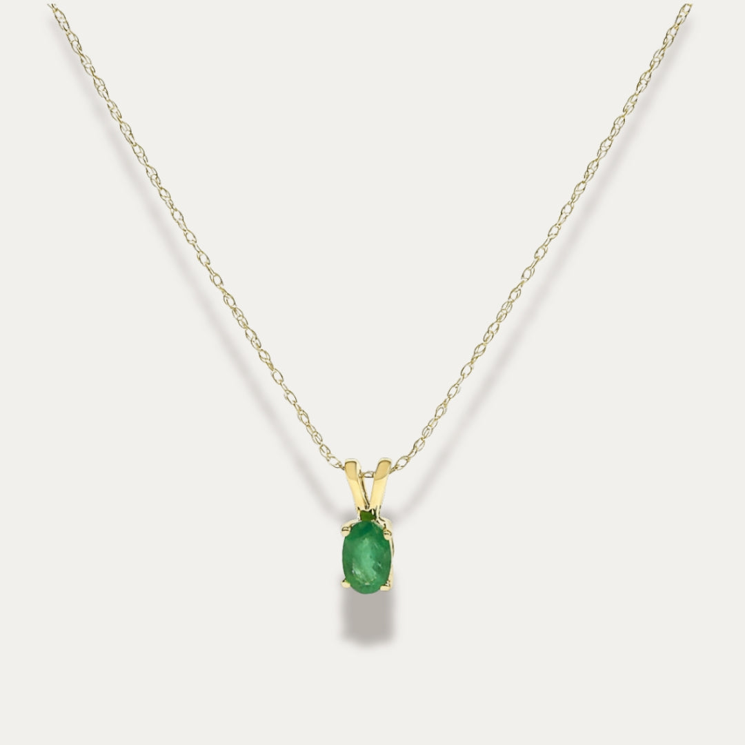Gold necklace with an emerald green gemstone pendant on a white background