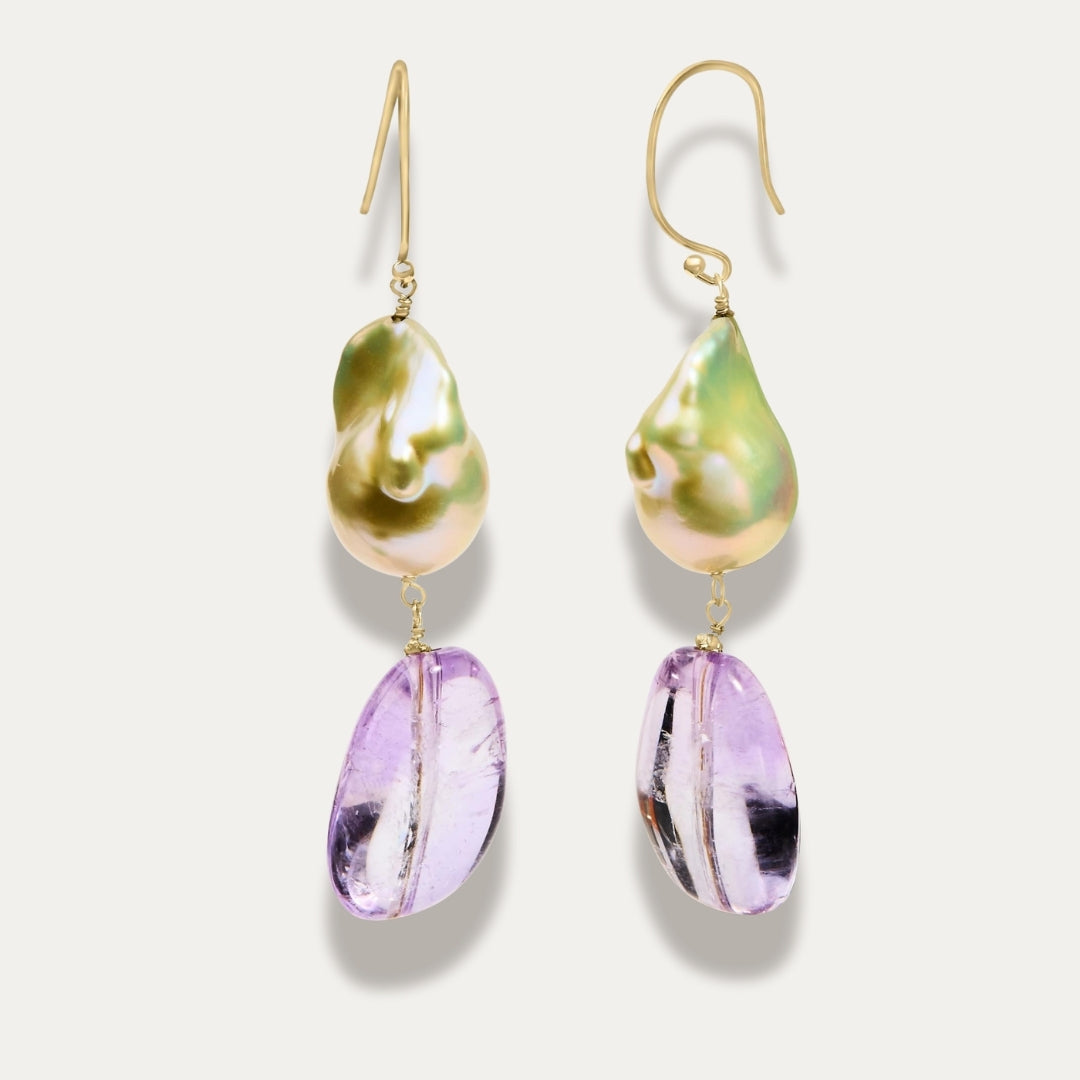 Pair of earrings with gold hooks, pearl and amethyst purple teardrop on a light grey background