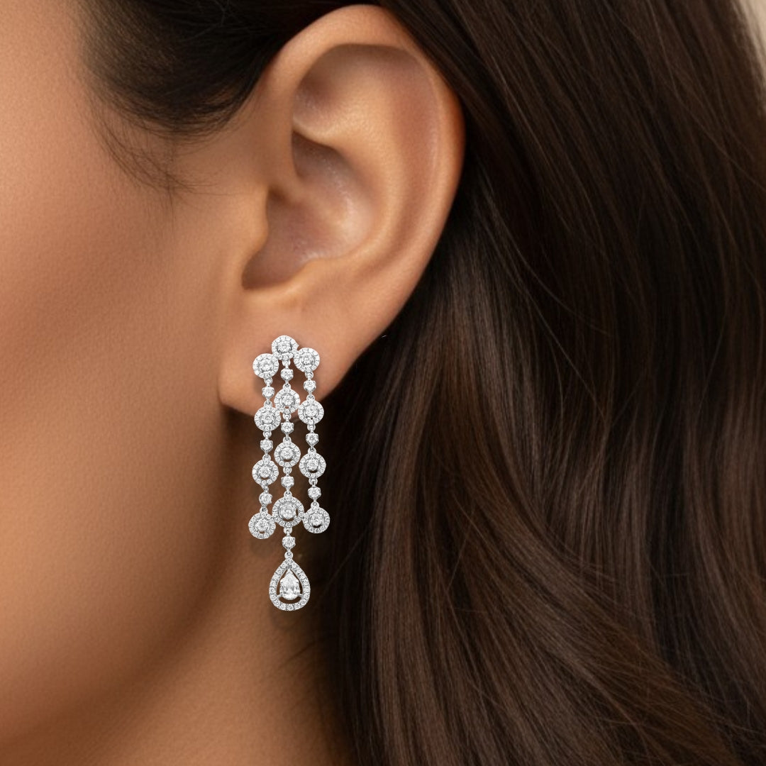 Close-up of a woman's ear wearing a diamond earring with dangling drops.