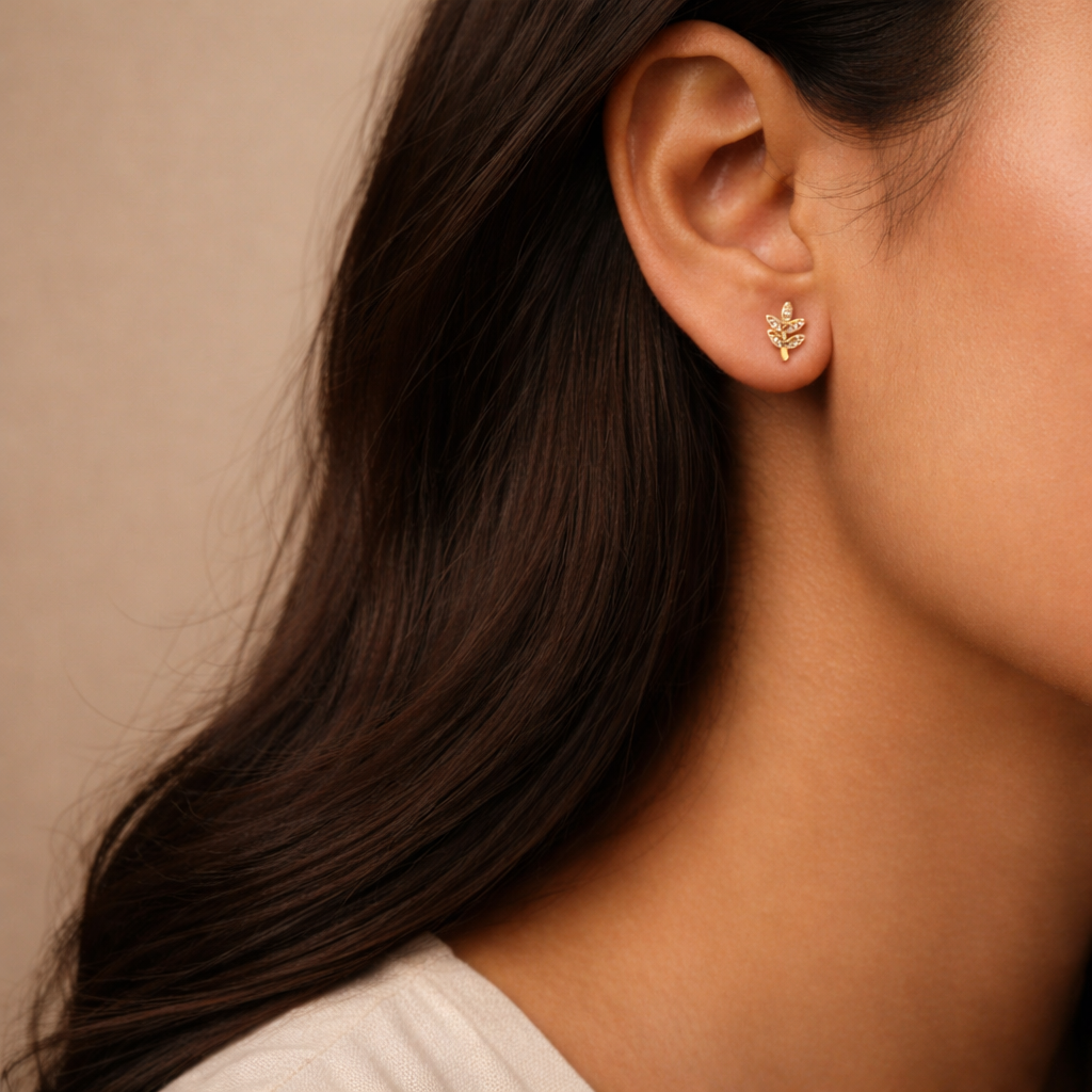 Close-up of an ear wearing a gold earring with a neutral background