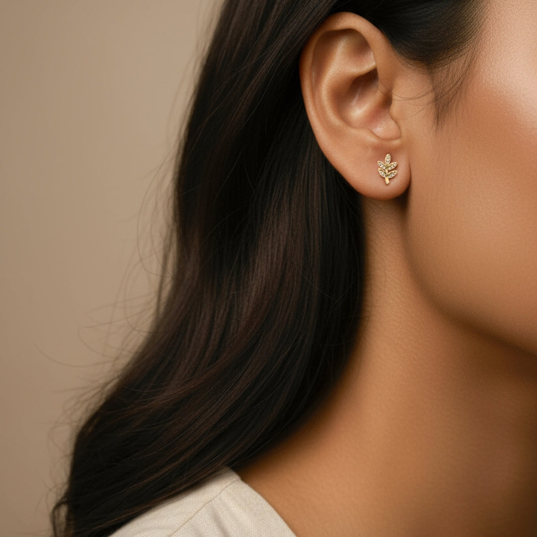 Close-up of an ear wearing a gold earring with a neutral background
