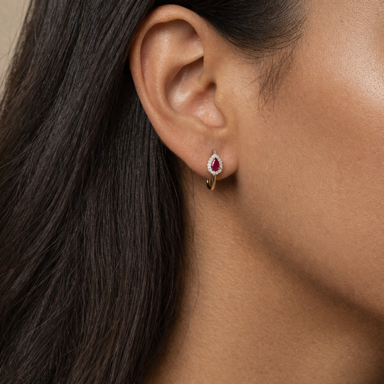 Close-up of a woman wearing a ruby earring with a neutral background