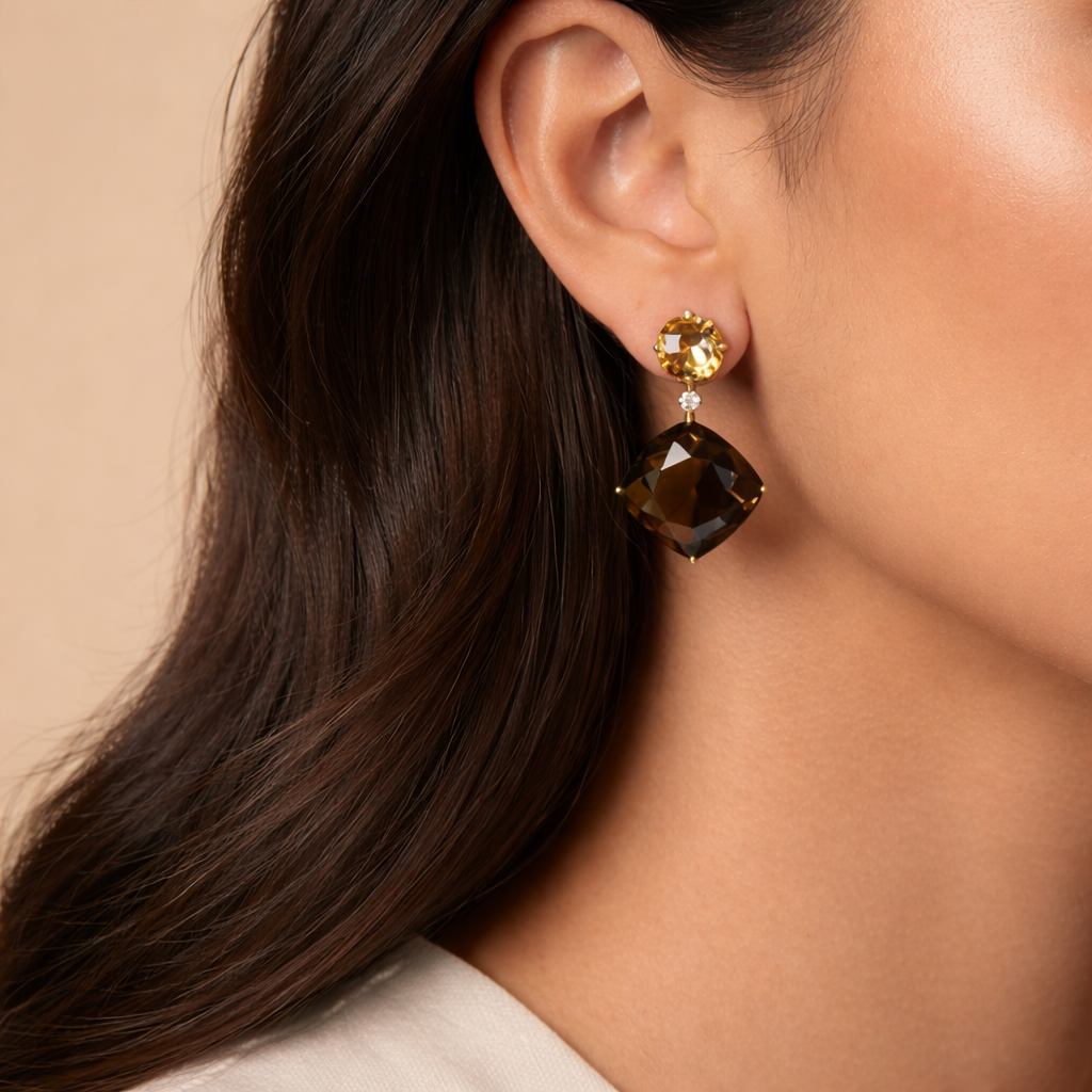 Close-up of a woman wearing 18k yellow gold dangle earrings featuring round checkerboard-cut yellow citrine, a single white diamond accent, and a large cushion-cut smoky quartz drop.