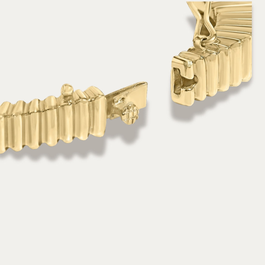 Close-up of the clasp of a gold bracelet on a light gray background