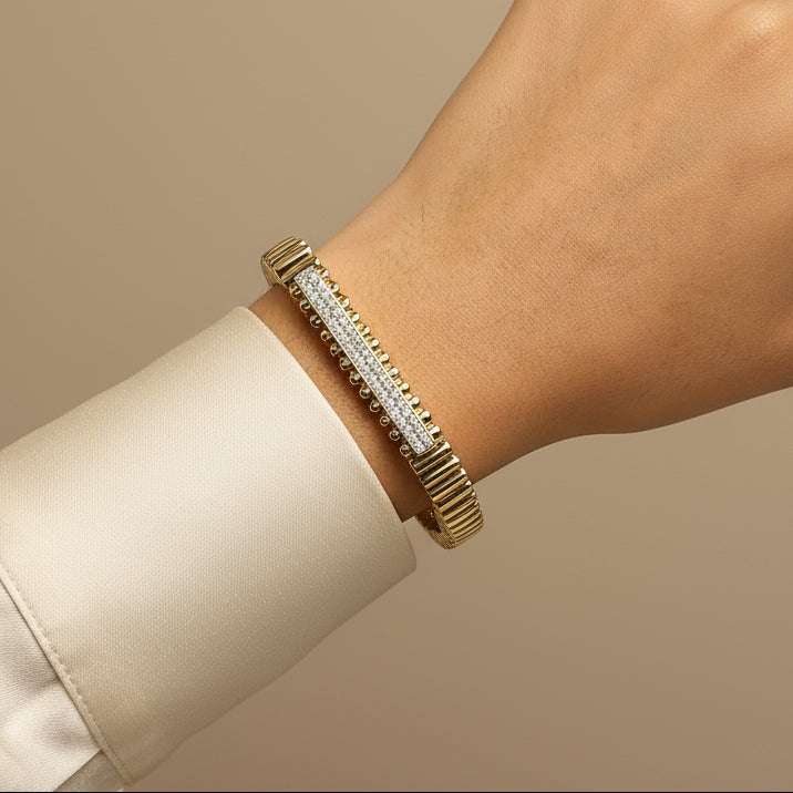 Gold bracelet with diamonds on a wrist against a beige background