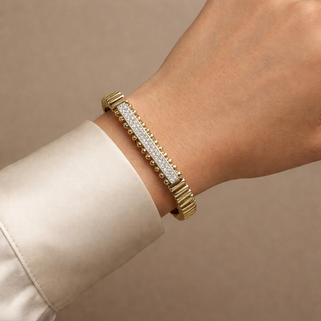 Gold bracelet with diamonds on a wrist against a beige background