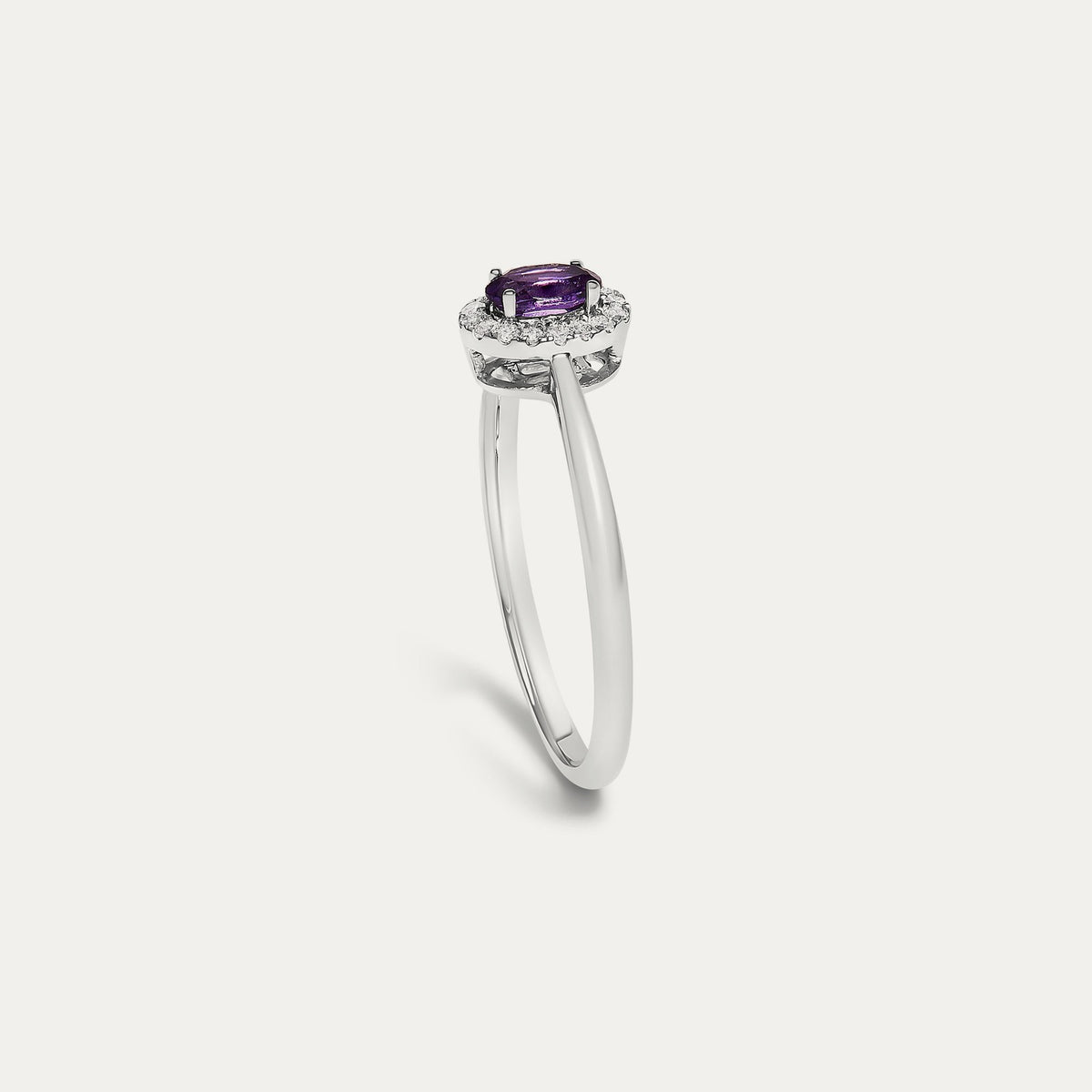 Profile view of the Origine birthstone halo ring in 10K white gold showing the raised halo setting with an oval amethyst above the slim band