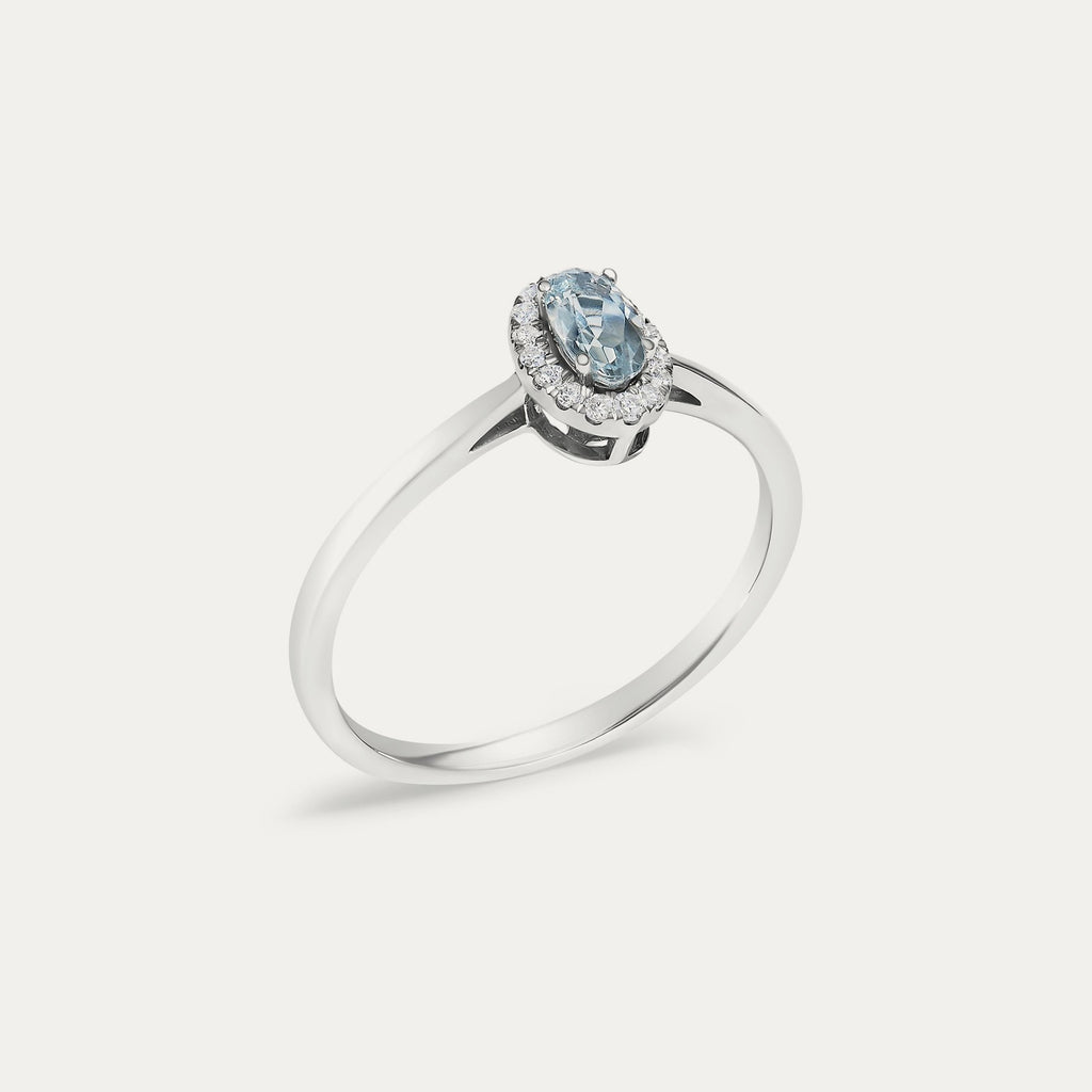Angled view of the Origine birthstone halo ring in 10K white gold with an oval aquamarine and its halo of natural diamonds