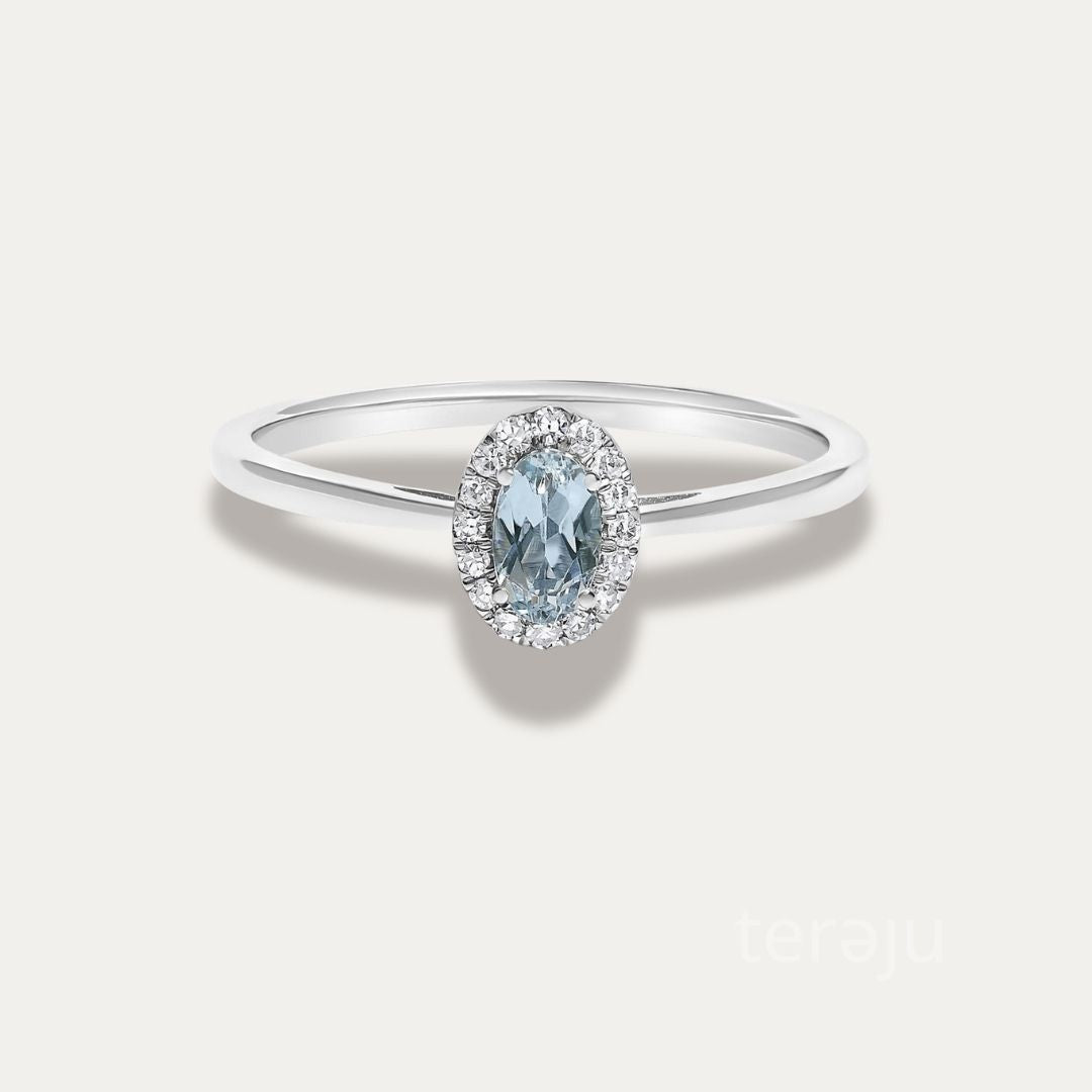 Front view of the Origine birthstone halo ring in 10K white gold with an oval aquamarine crowned by a halo of natural diamonds
