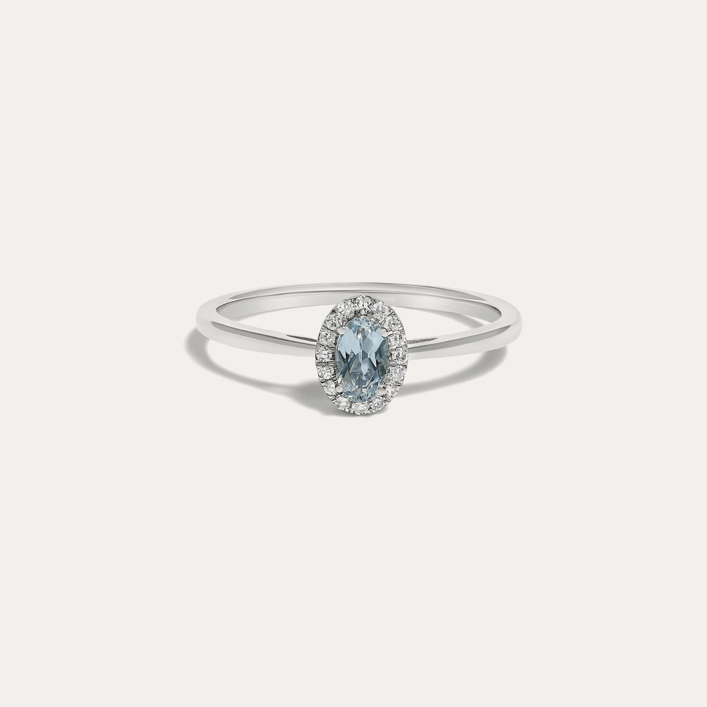 Front view of the Origine birthstone halo ring in 10K white gold with an oval aquamarine crowned by a halo of natural diamonds