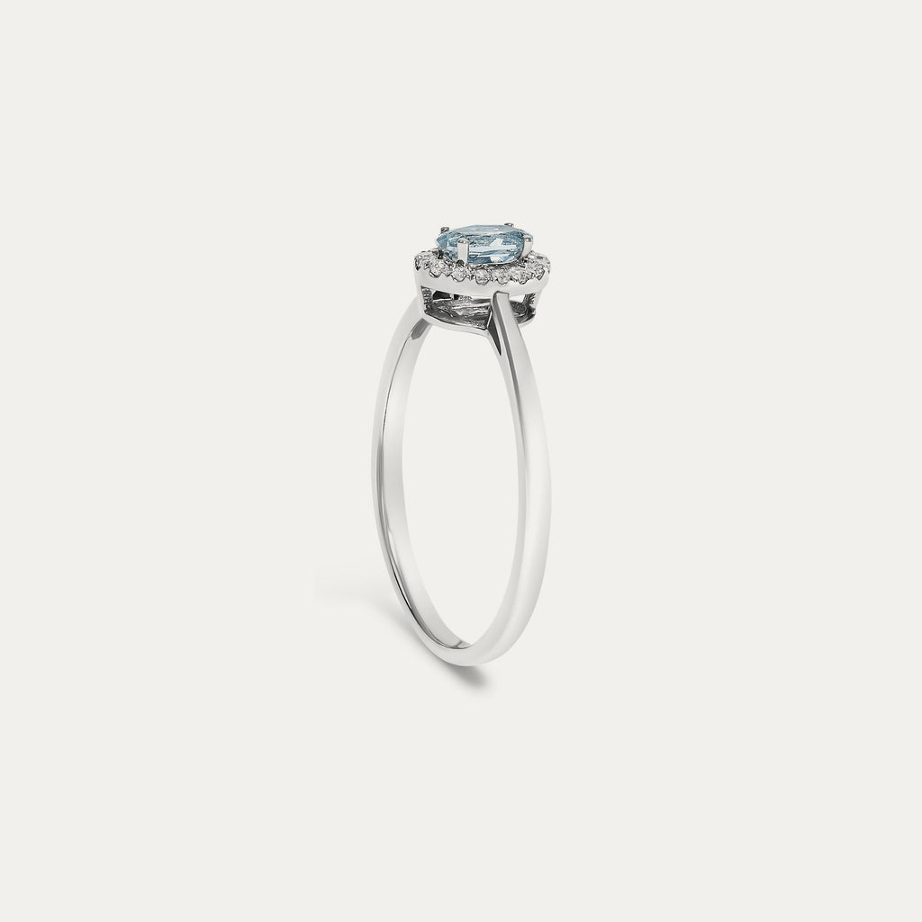 Profile view of the Origine birthstone halo ring in 10K white gold showing the raised halo setting with an oval aquamarine above the slim band