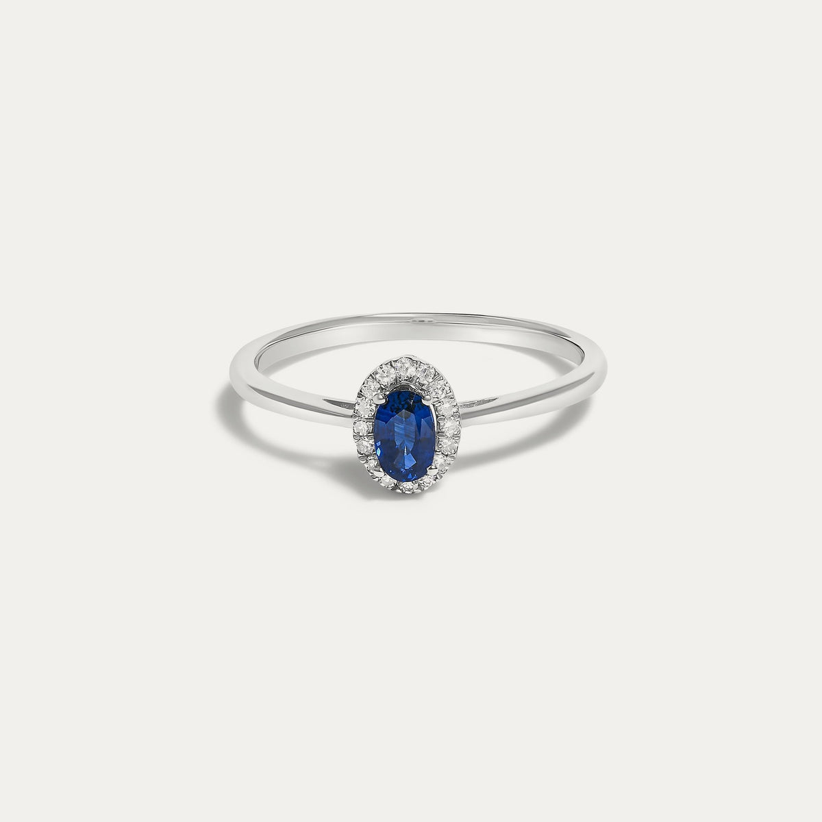 Front view of the Origine birthstone halo ring in 10K white gold with an oval blue sapphire crowned by a halo of natural diamonds
