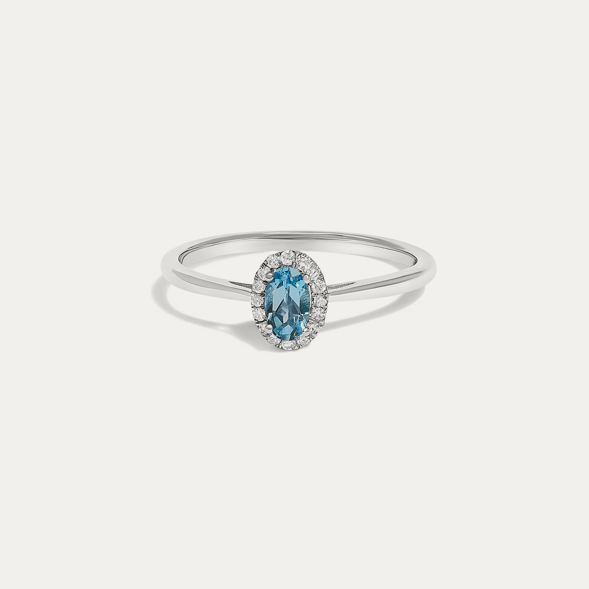 Front view of the Origine birthstone halo ring in 10K white gold with an oval blue topaz crowned by a halo of natural diamonds