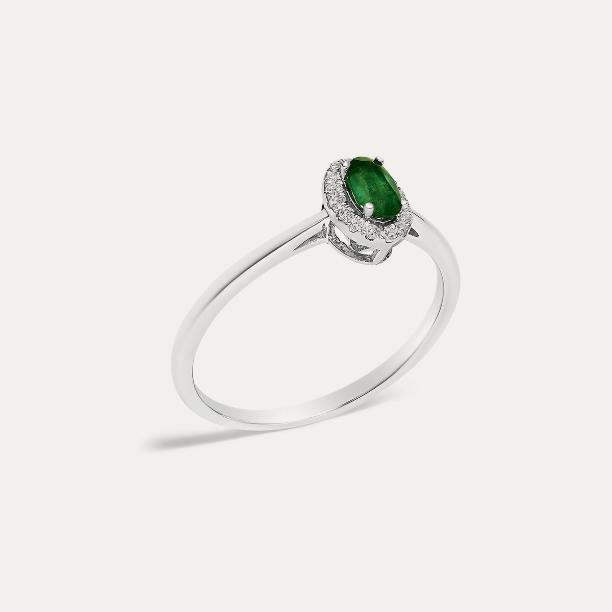 Angled view of the Origine birthstone halo ring in 10K white gold with an oval emerald and its halo of natural diamonds