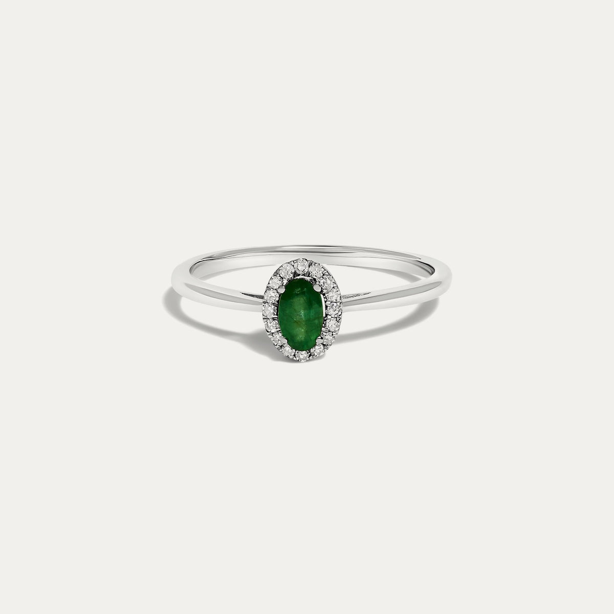 Front view of the Origine birthstone halo ring in 10K white gold with an oval emerald crowned by a halo of natural diamonds