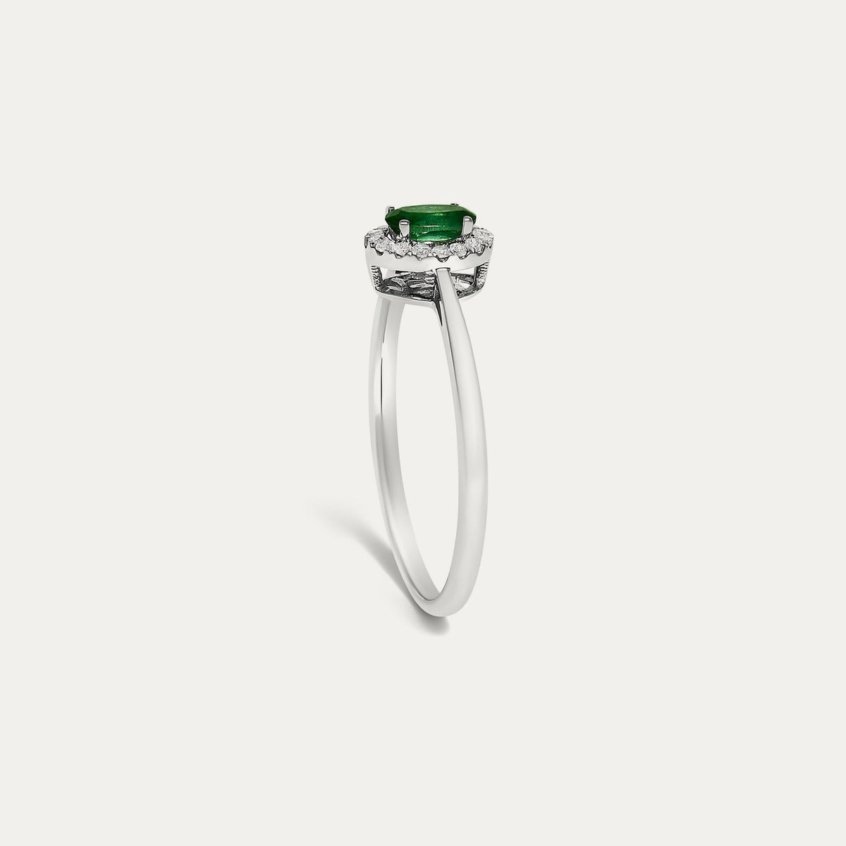 Profile view of the Origine birthstone halo ring in 10K white gold showing the raised halo setting with an oval emerald above the slim band