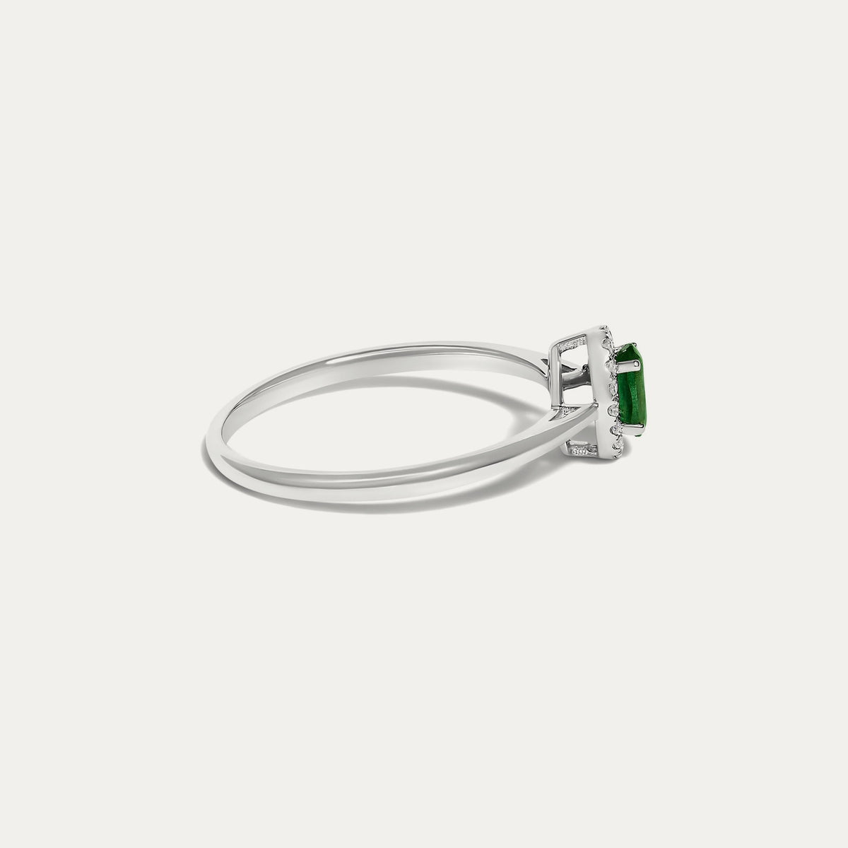 Side view of the Origine birthstone halo ring in 10K white gold with an oval emerald and a halo of natural diamonds above the slim band