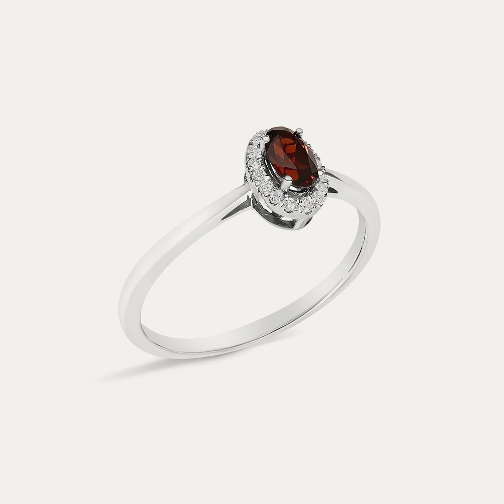 Angled view of the Origine birthstone halo ring in 10K white gold with an oval garnet and its halo of natural diamonds