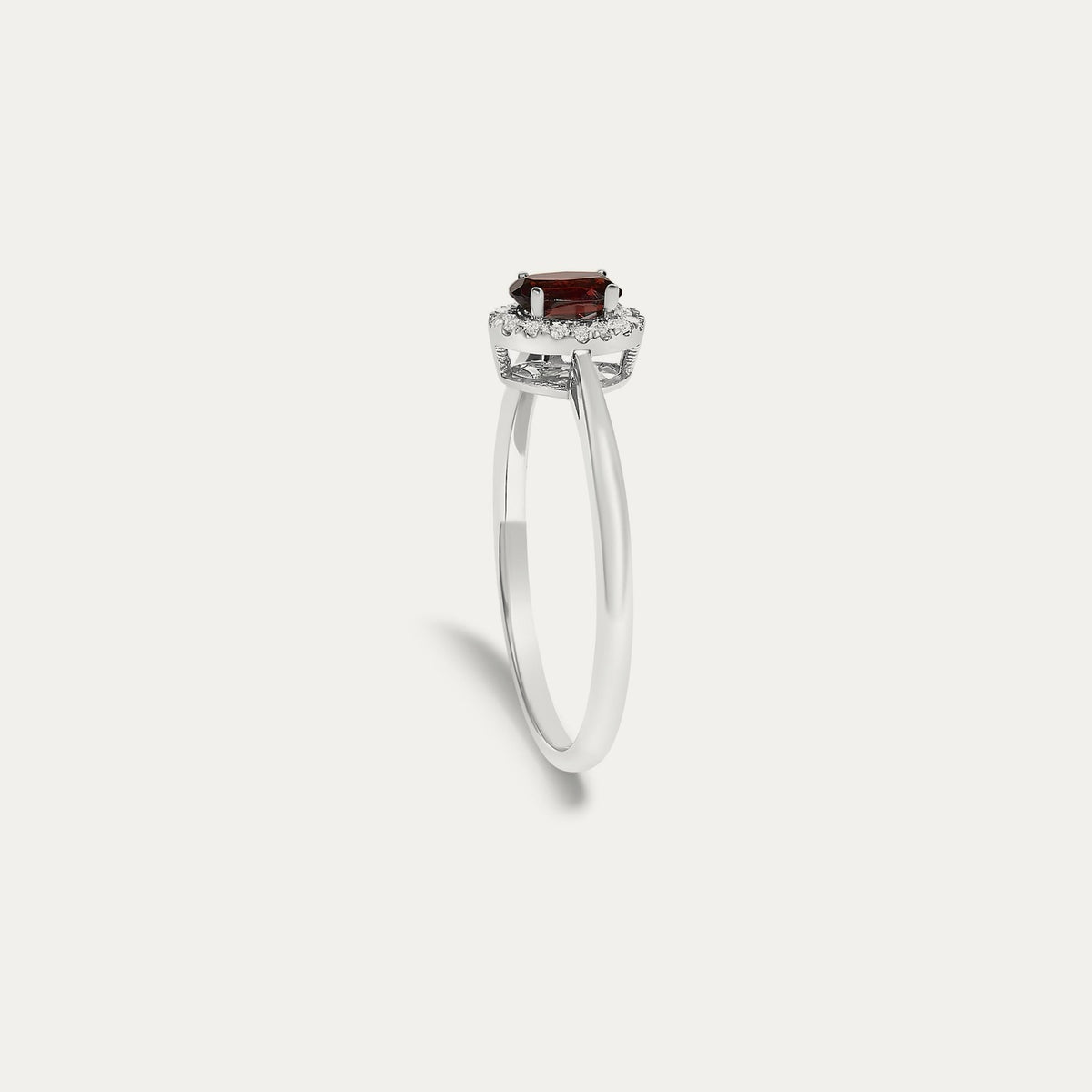 Profile view of the Origine birthstone halo ring in 10K white gold showing the raised halo setting with an oval garnet above the slim band