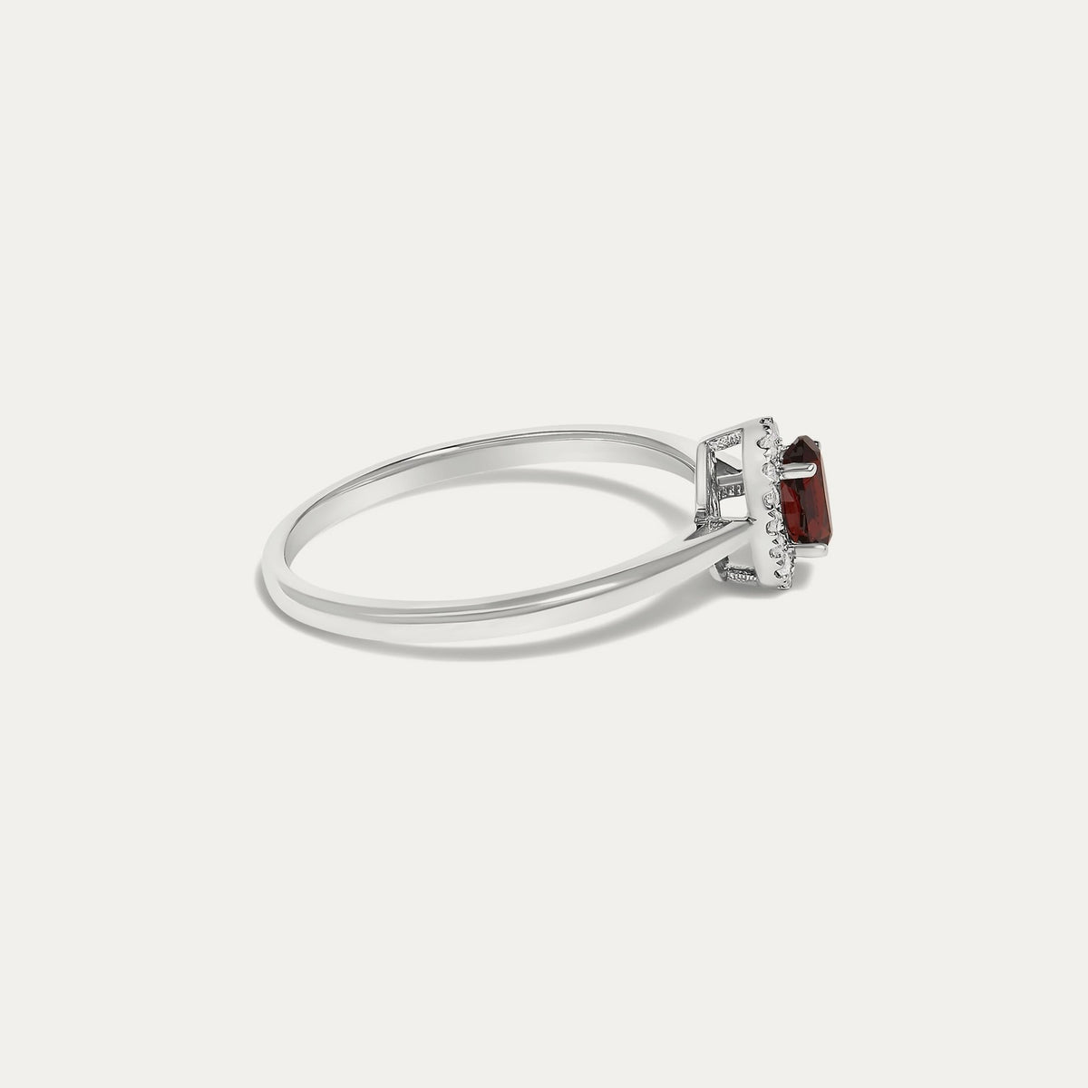 Side view of the Origine birthstone halo ring in 10K white gold with an oval garnet and a halo of natural diamonds above the slim band