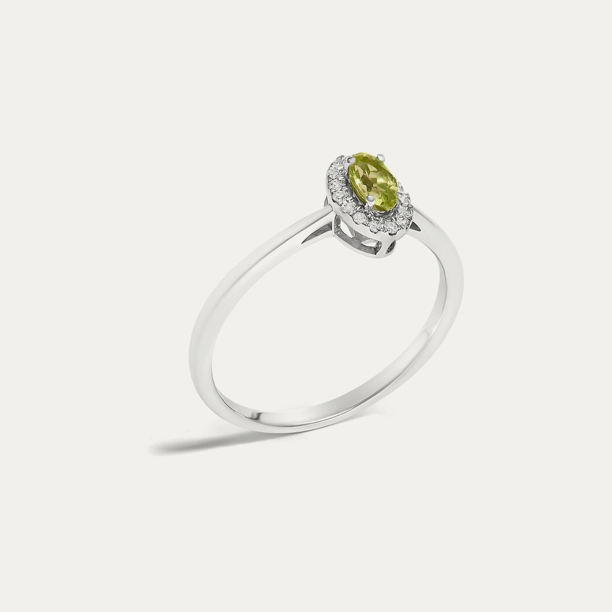 Angled view of the Origine birthstone halo ring in 10K white gold with an oval peridot and its halo of natural diamonds